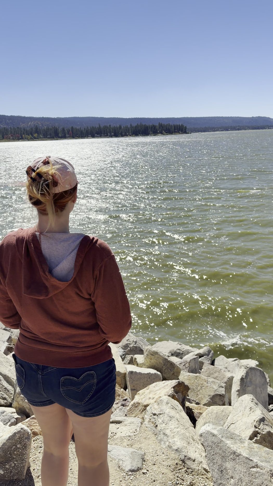 Jenna from behind, standing on the rocks and looking out across the lake