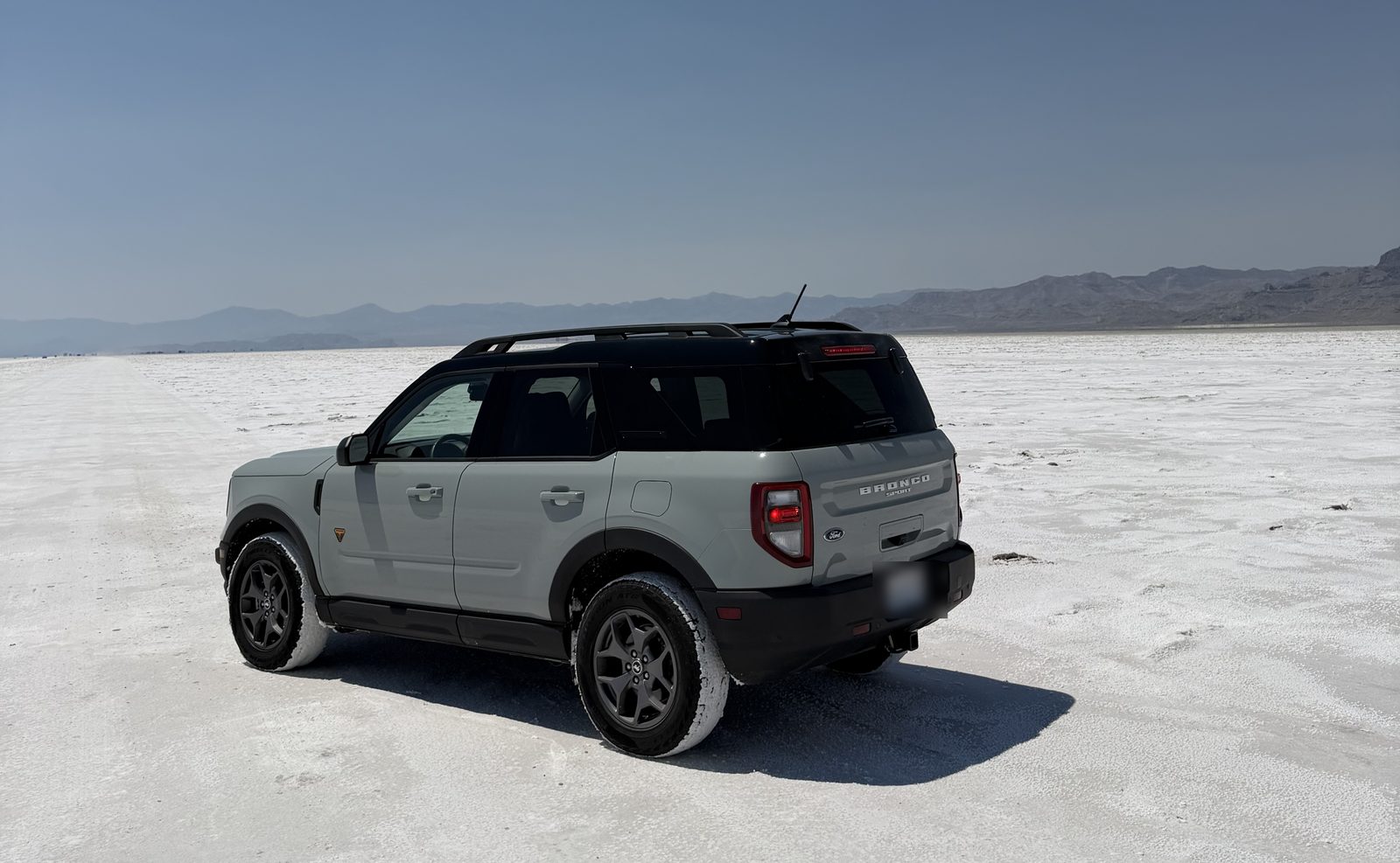 Daisy, a pale sage Bronco Sport, parked alone on the salt flats with white salt running out to distant mountains on every side