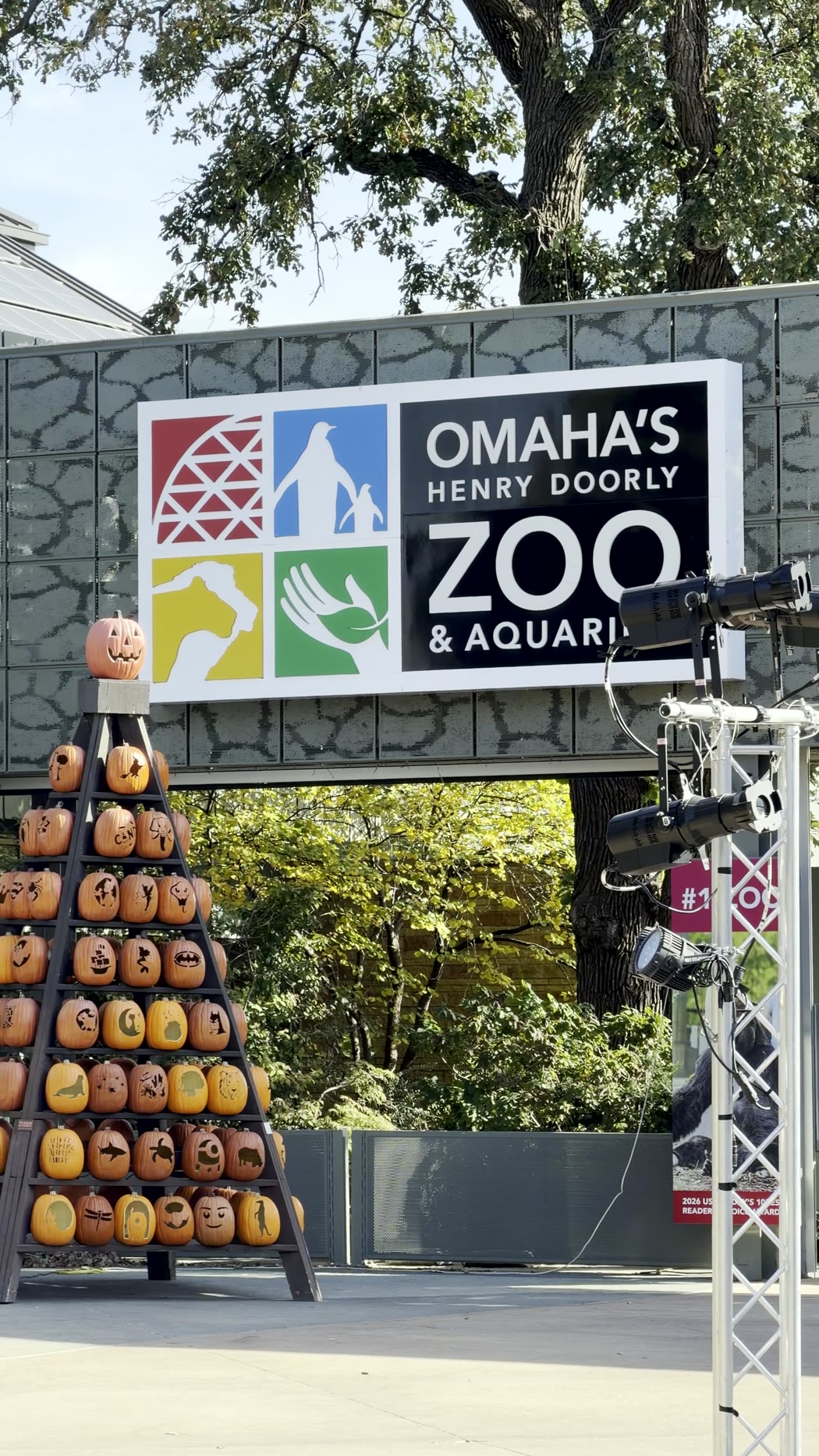 The Omaha's Henry Doorly Zoo and Aquarium entrance sign beside a tower of carved pumpkins