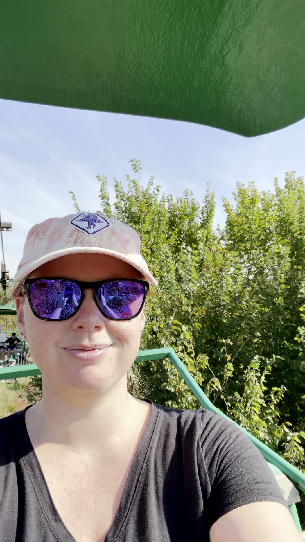 Jenna in a cap and sunglasses on the Skyfari, trees behind her