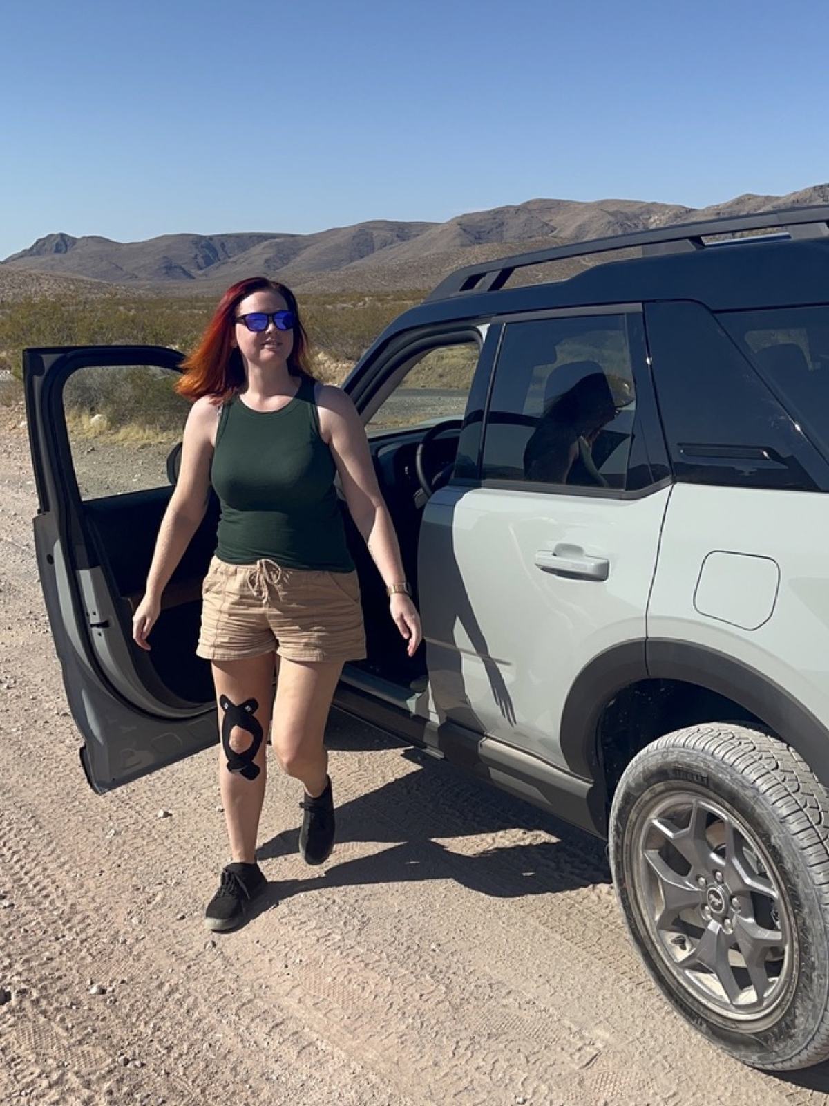 Jenna stepping out of Daisy, her grey Bronco Sport, on a dirt road
