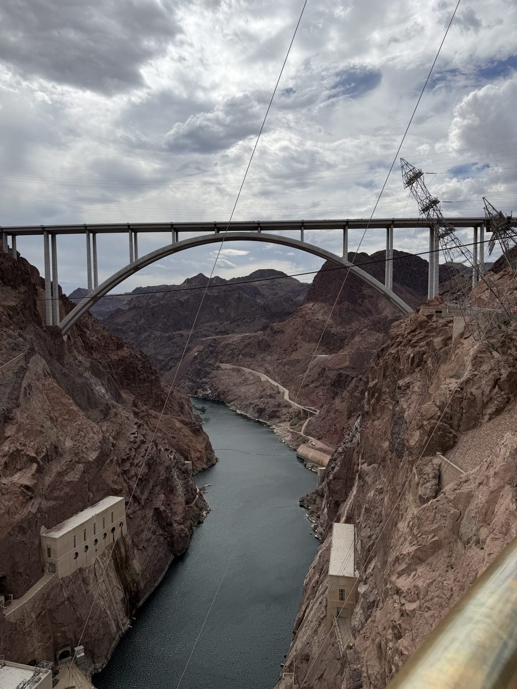 The Colorado River running down a steep canyon under a high concrete arch bridge