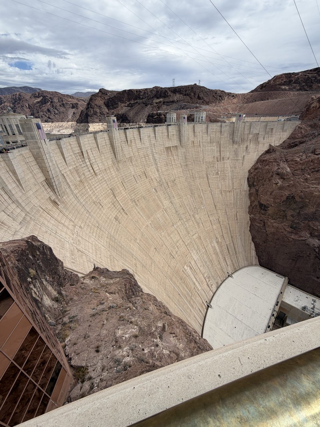 The curved concrete face of Hoover Dam dropping away into the canyon below