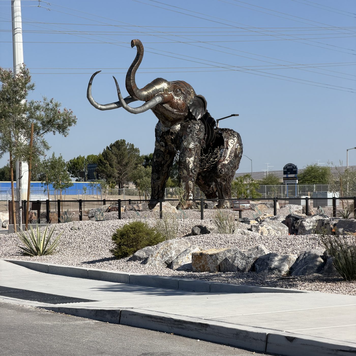 A life-size metal sculpture of a mammoth with raised tusks beside the park road