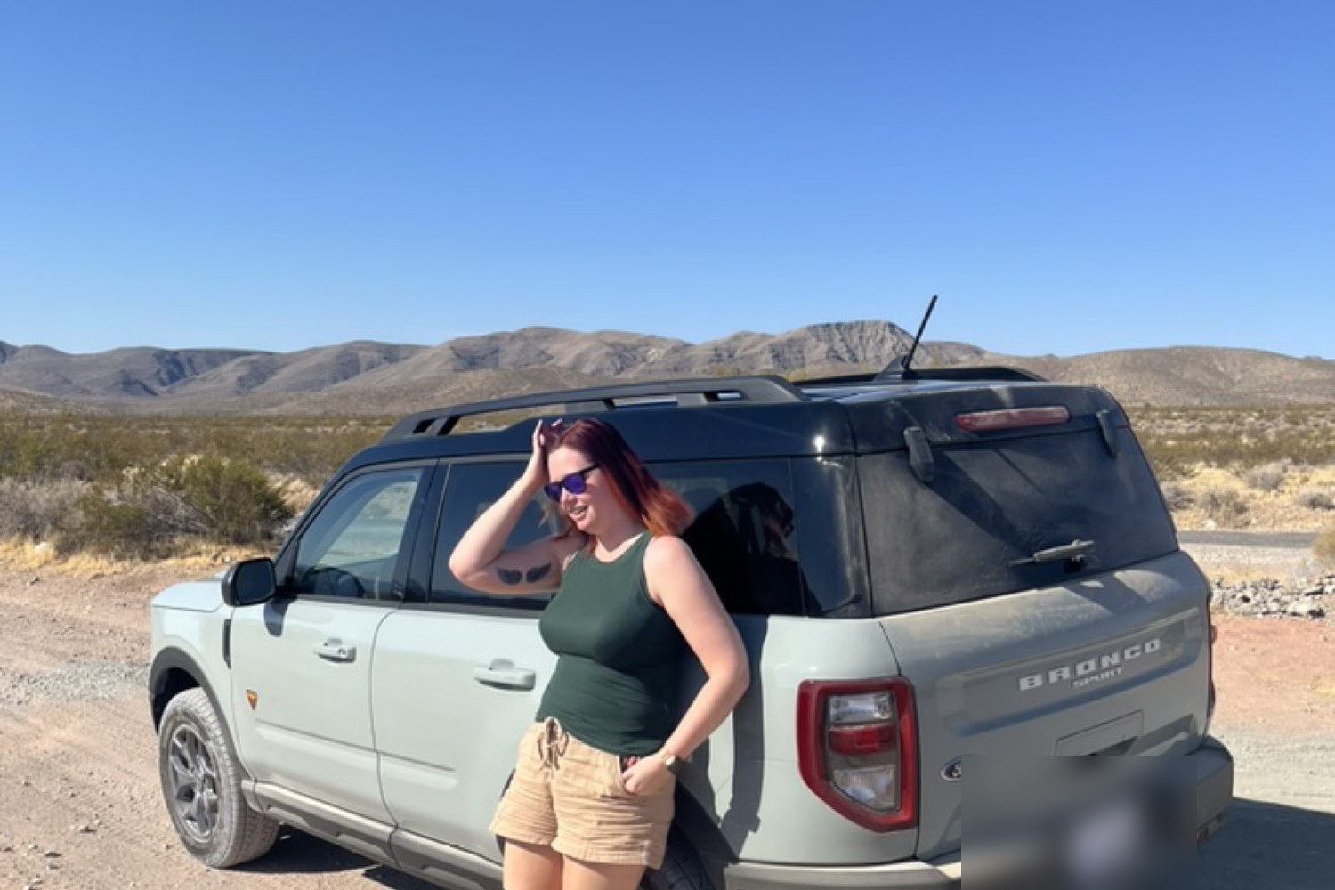 Leaning against Daisy on a desert pullout, mountains rising behind