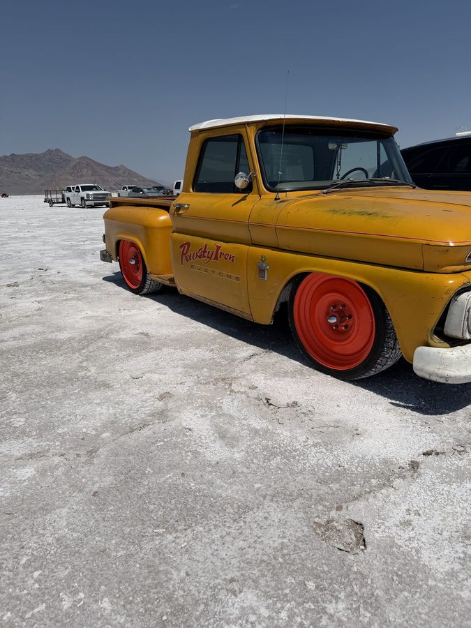 A yellow pickup with red wheels on the salt