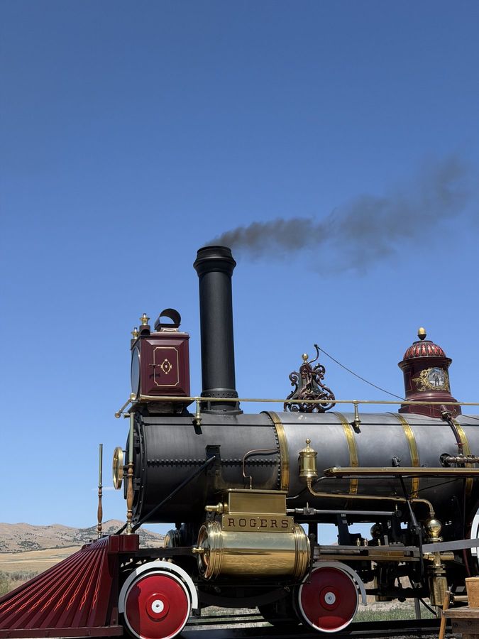 A steam locomotive under way with a plume of smoke