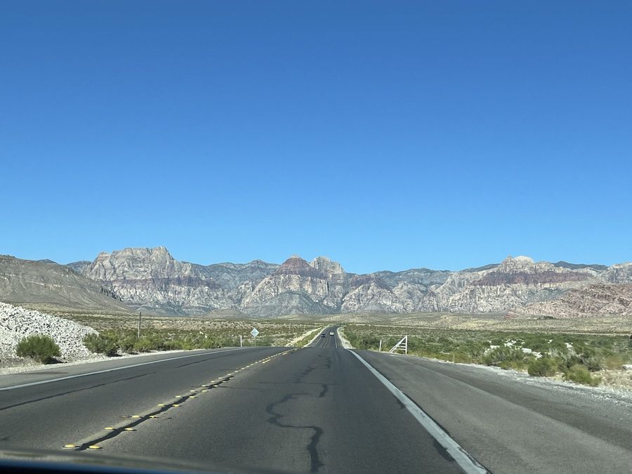 A desert highway running toward red and grey mountains