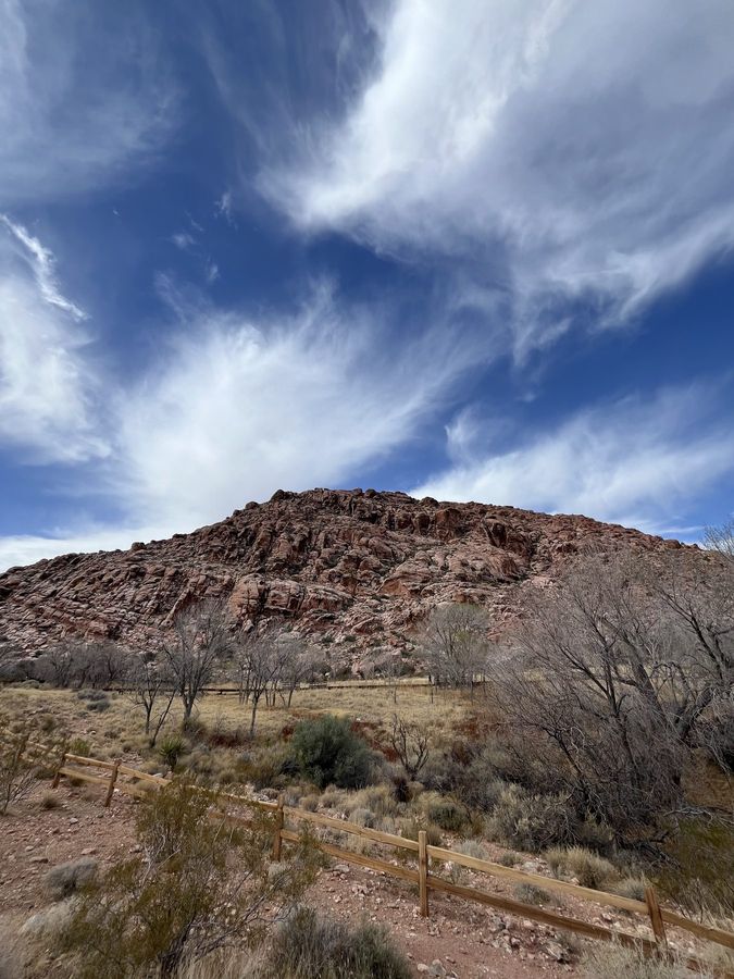 Streaked cirrus clouds over a red hillside