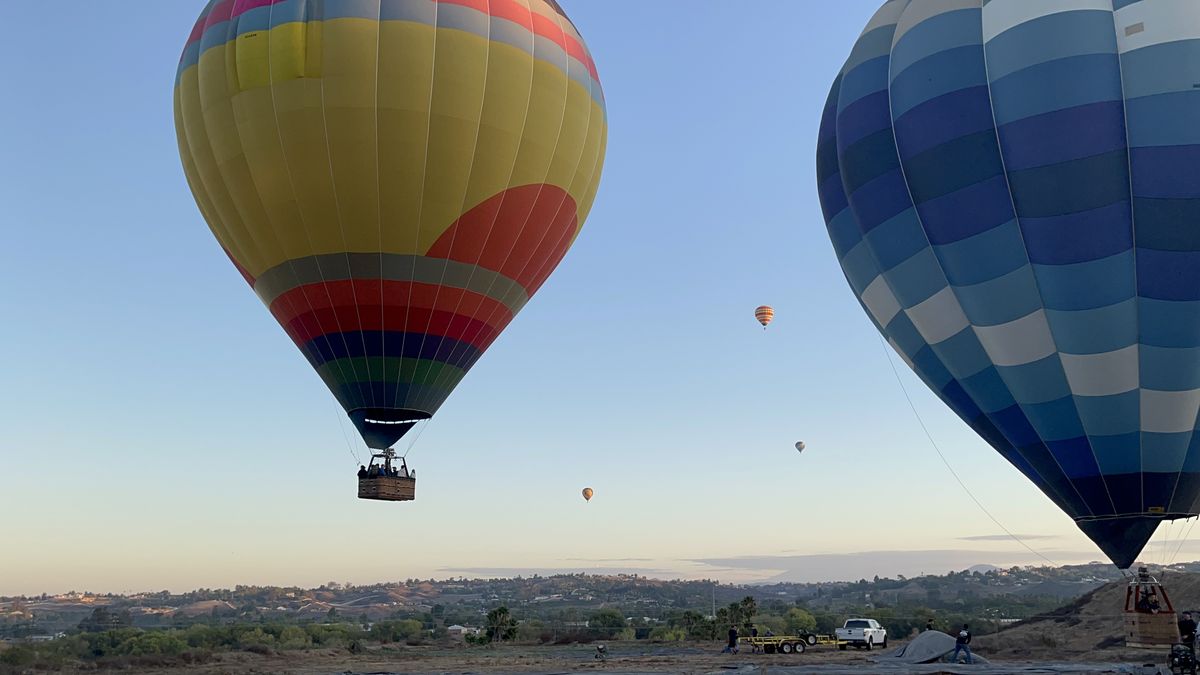 Two hot air balloons aloft at dawn over open country